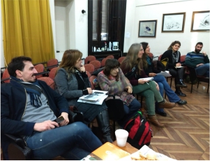 La imagen muestra a los participantes de la reunión en un aula de la facultad, sentados en círculo y conversando.